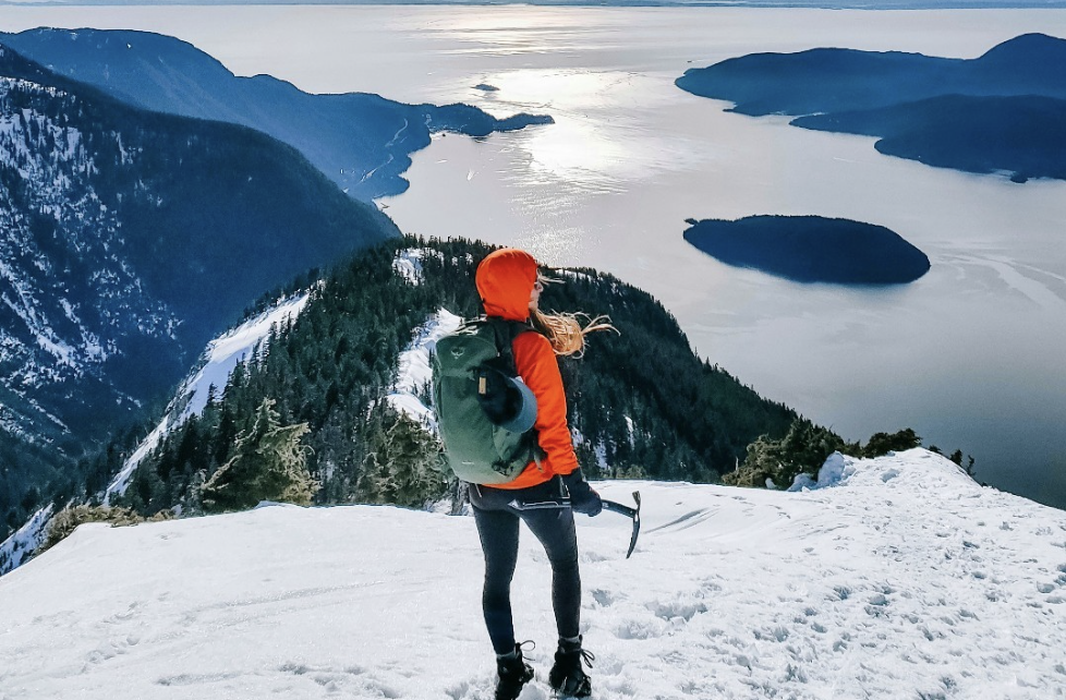 Image of person standing on a snow-covered mountain wearing an Osprey Backpack curated by Swagger.
