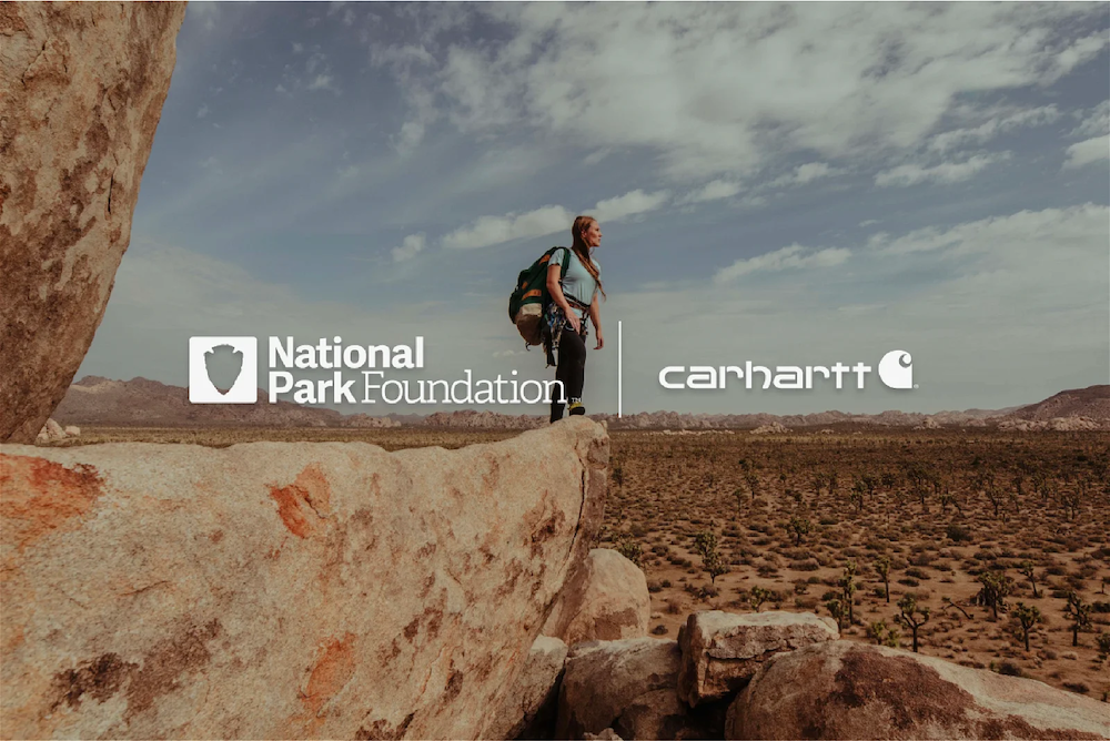National Park Foundation and Carhartt logos with woman standing on a rock in the middle of the desert.