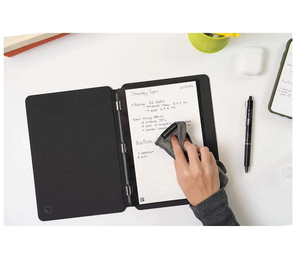 A custom branded Rocketbook notebook with notes written on the surface and a pen next to the Rocketbook.