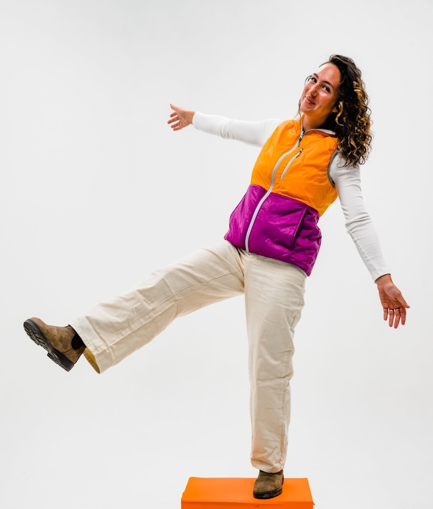 Woman standing on one foot wearing the Reversible Synthetic Vest curated by Swagger.