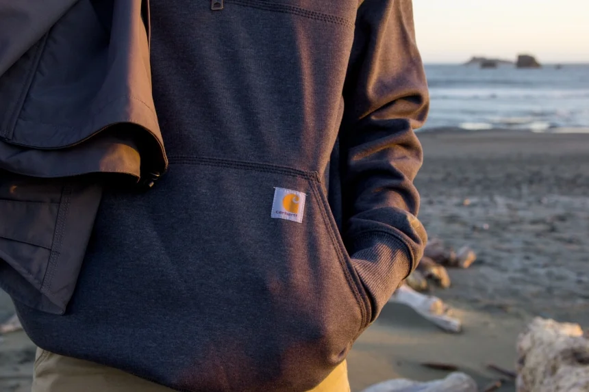 Man in Carhartt sweatshirt standing on the beach can be custom branded by Swagger.