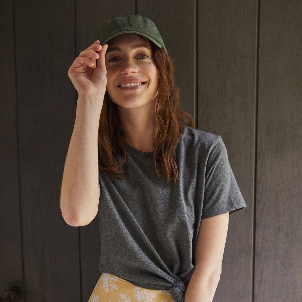 Woman smiling at the camera and holding her hat wearing the Alternative Apparel Earthleisure Triblend Tee curated by Swagger.
