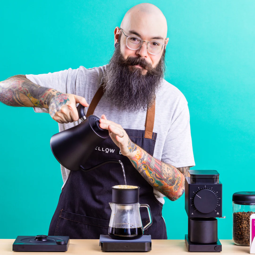 Man with tattoos pouring from the Stagg EKG Electric Pour-Over Kettle into the Stagg Pour Over set can be designed and curated by Swagger.