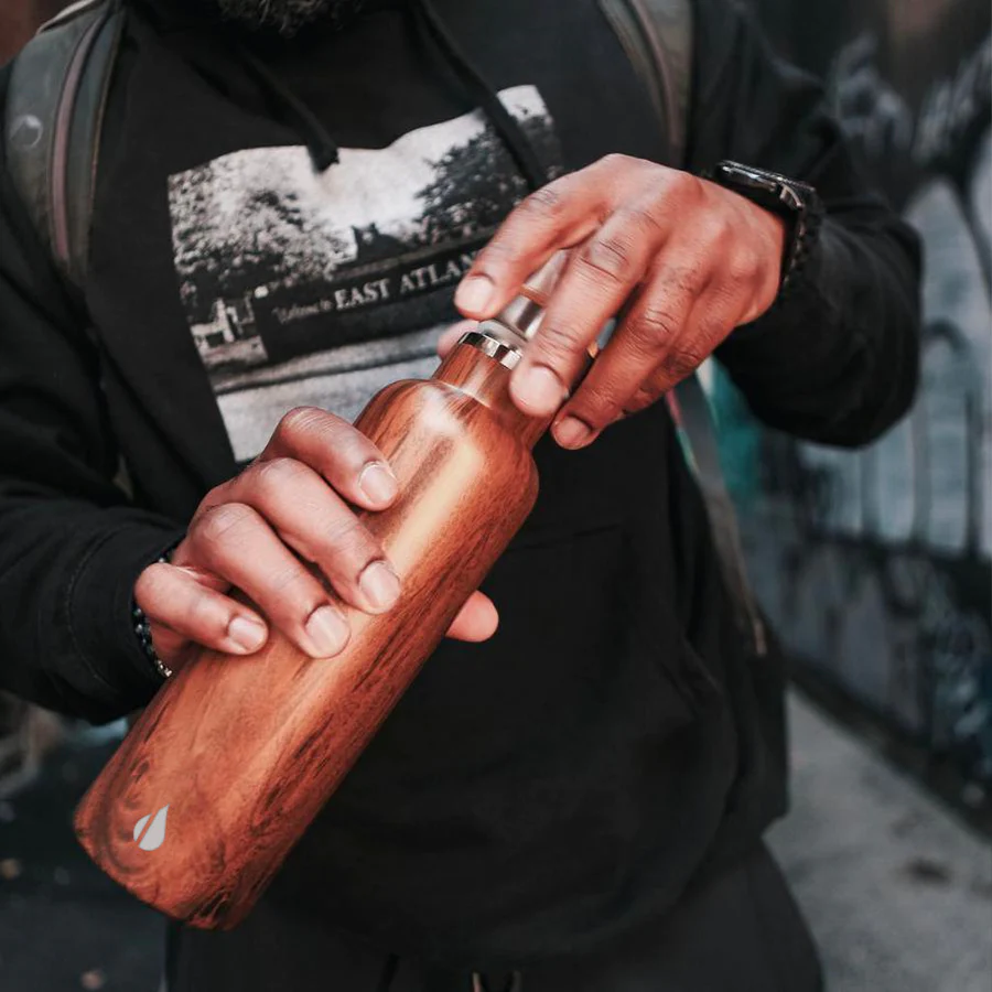 Image of a man holding teakwood Elemental water bottle.