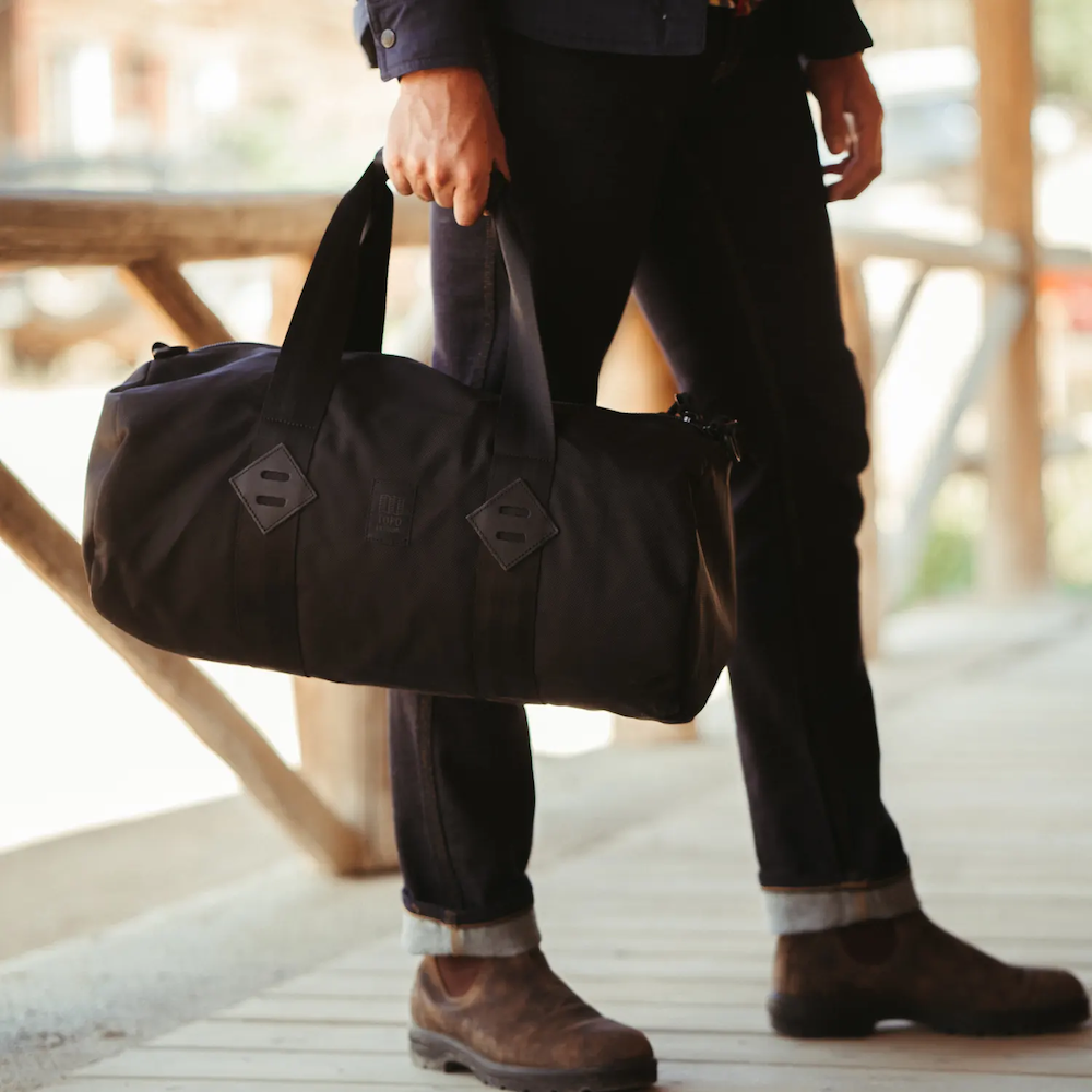 A Topo Designs Classic Duffle displayed against an urban backdrop, designed by Swagger.
