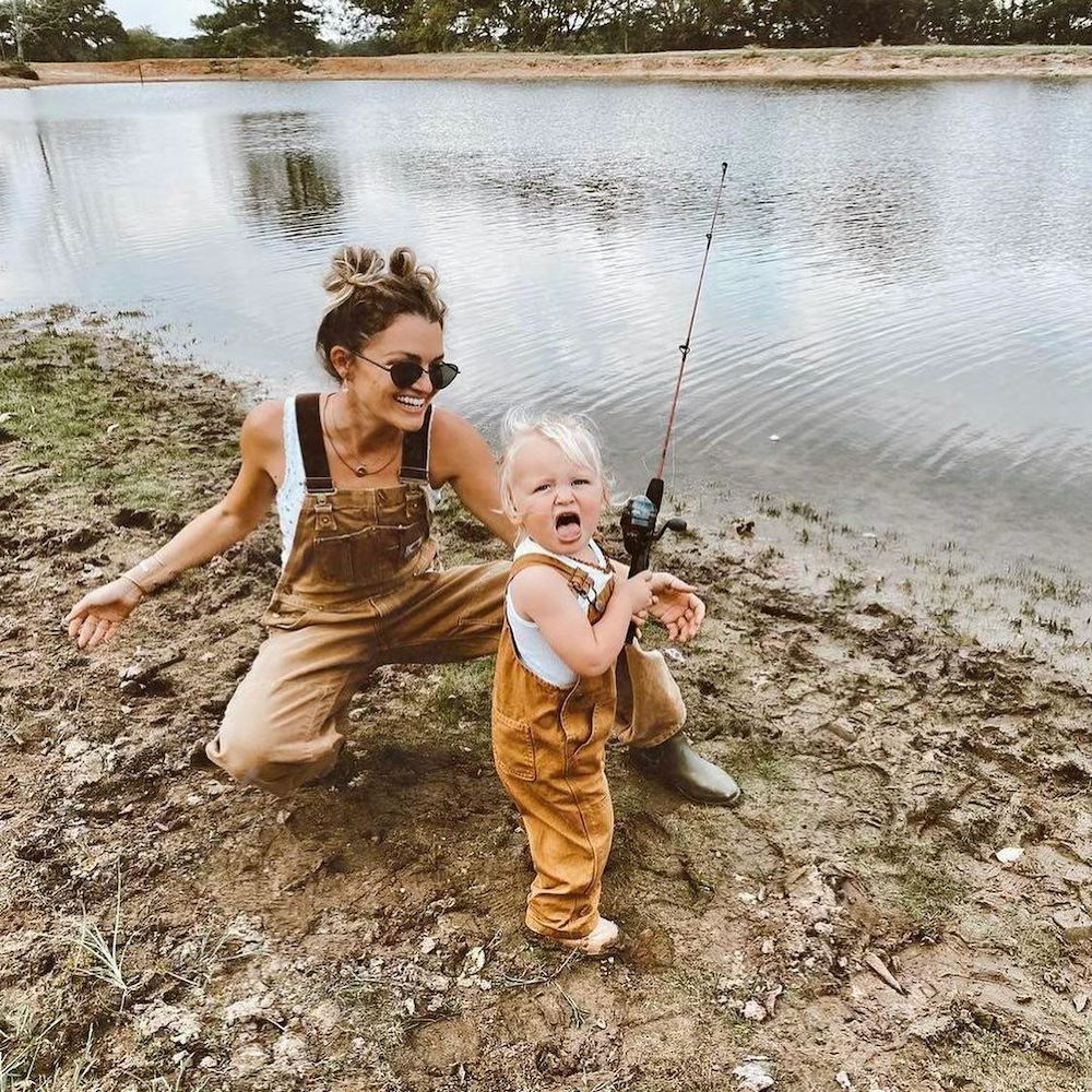 Mom and baby both in Carhartt bib overalls fishing on a lake can be custom branded by Swagger.